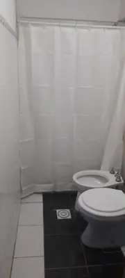 a white bathroom with a toilet and a shower at Cabañas cochico in Villa Carlos Paz