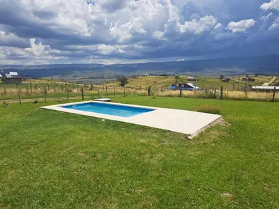 a swimming pool in the middle of a grass field at Ullasa - Casa de Montaña in Villa Yacanto