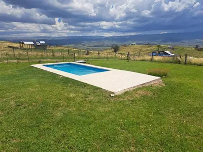 a swimming pool in the middle of a grass field at Ullasa - Casa de Montaña in Villa Yacanto