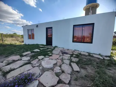 a white house with a stone walkway in front of it at El descanso casita en alquiler in Taninga