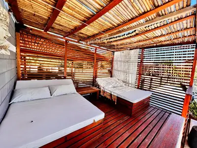a wooden balcony with two beds and a wooden roof at Carpe Diem Cabañas en Panaholma in Panaholma