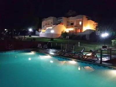 a swimming pool with chairs and a building at night at El Cabañal in Mina Clavero