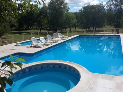 a large blue swimming pool with lounge chairs next to it at El Cabañal in Mina Clavero