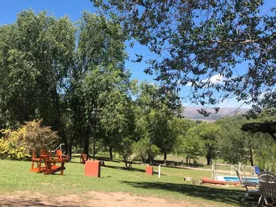 a park with benches and a playground in the grass at El Cabañal in Mina Clavero