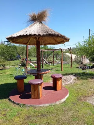 a playground with a table and two stools under an umbrella at Cabañas Vicentico in Mina Clavero