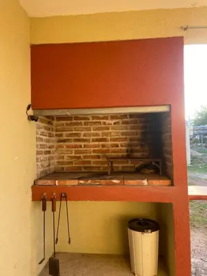 a brick fireplace in a room with a trash can at Cabañas Vicentico in Mina Clavero