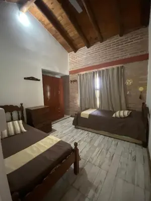 a bedroom with two beds and a wooden floor at Cabañas Vicentico in Mina Clavero