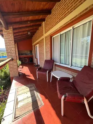 a porch with two chairs and a table and windows at Cabañas Vicentico in Mina Clavero
