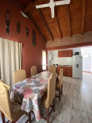 a dining room with a table and a kitchen at Cabañas Vicentico in Mina Clavero