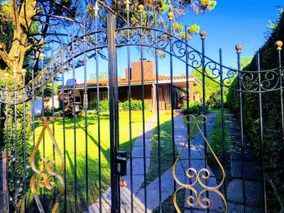a gate to a garden with a building behind it at Casa frente al rio San Antonio Playas de Oro Villa Carlos Paz in Villa Carlos Paz