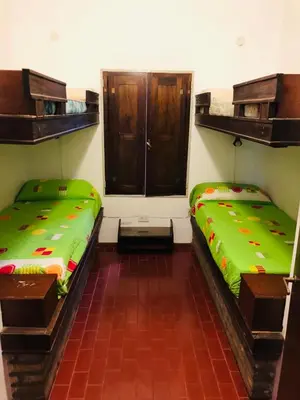 two beds in a room with green sheets at Casa frente al rio San Antonio Playas de Oro Villa Carlos Paz in Villa Carlos Paz