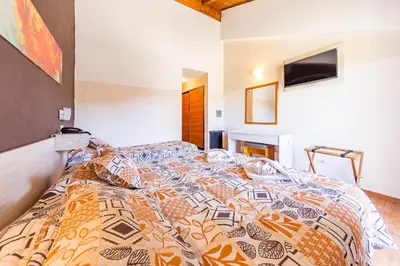 a bedroom with a bed with a comforter on it at Costanera Hotel in Villa Carlos Paz
