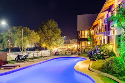 a swimming pool in front of a building at night at Costanera Hotel in Villa Carlos Paz