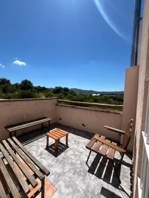 two benches and a table on a balcony at Cabañas aires de montaña in Villa Parque Siquiman