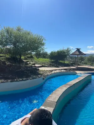 a person taking a picture of a swimming pool at Cabañas aires de montaña in Villa Parque Siquiman