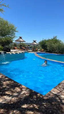 a person swimming in a blue swimming pool at Cabañas aires de montaña in Villa Parque Siquiman