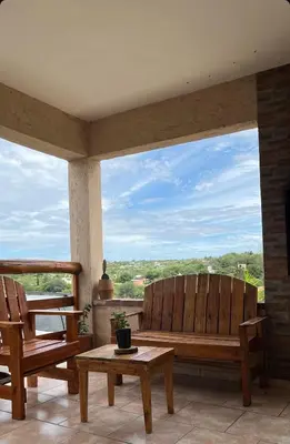 a porch with two wooden benches and a table at Cabañas aires de montaña in Villa Parque Siquiman