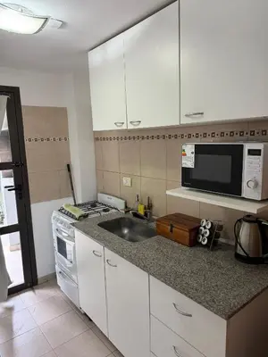 a kitchen with white cabinets and a sink and a microwave at Cabañas Don Carlos in Villa Carlos Paz