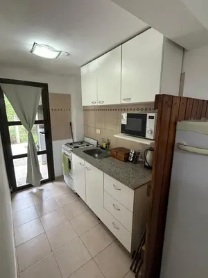 a kitchen with white cabinets and a sink and a refrigerator at Cabañas Don Carlos in Villa Carlos Paz