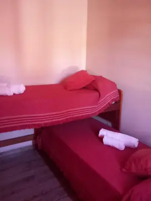 two beds in a room with red sheets at 2 Dormitorios y pileta in Villa Anizacate