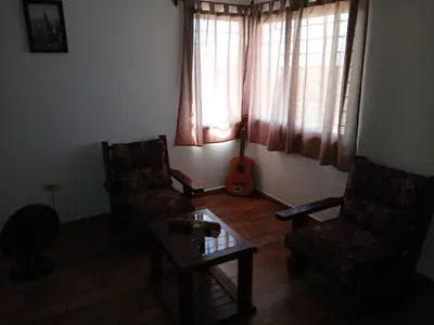 a living room with two chairs and a guitar at 2 Dormitorios y pileta in Villa Anizacate