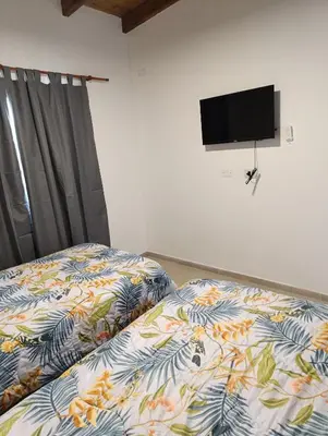 a bedroom with two beds and a flat screen tv at Yatel in Santa Rosa de Calamuchita