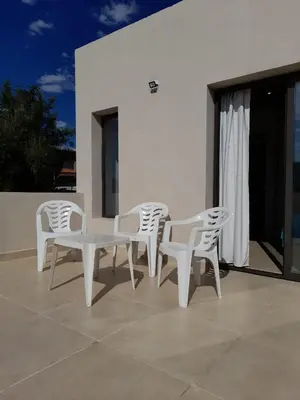 a group of white chairs and a table on a patio at Casa Sol Serrano - con todas las comodidades y excelente ubicación in Villa Carlos Paz