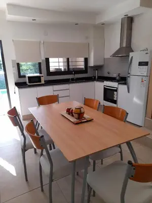a kitchen with a wooden table with chairs and a refrigerator at Casa Sol Serrano - con todas las comodidades y excelente ubicación in Villa Carlos Paz
