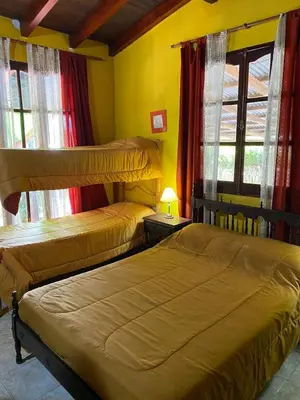 two beds in a room with yellow walls and windows at Paseo por las Nubes in Santa Rosa de Calamuchita
