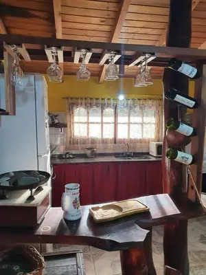 a kitchen with a table and a counter with wine bottles at Paseo por las Nubes in Santa Rosa de Calamuchita