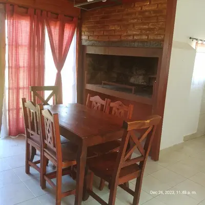 a dining room table with chairs and a fireplace at Cabaña del mallin in Bialet Massé