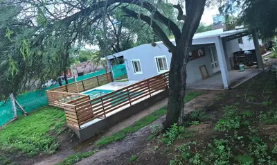a house with a wooden fence and a swimming pool at Cabañas Mimi in Villa Anizacate