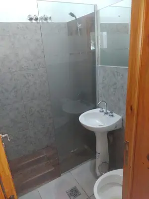 a bathroom with a shower and a sink and a toilet at Cabañas Mimi in Villa Anizacate