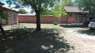 a yard with a tree and chairs and a building at Residencial El Amancer in Mina Clavero