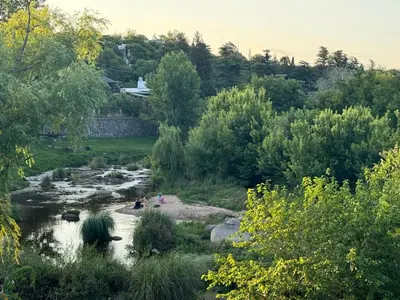a group of people sitting on the shore of a river at Cabañas vizcarra in Villa Carlos Paz
