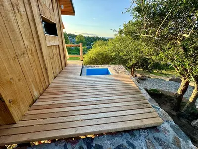 a wooden deck with a pool next to a building at Cabañas vizcarra in Villa Carlos Paz