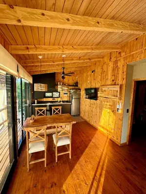 a dining room with a wooden table and a kitchen at Cabañas vizcarra in Villa Carlos Paz