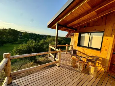 a porch of a wooden cabin with a fence and chairs at Cabañas vizcarra in Villa Carlos Paz