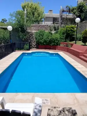 a blue swimming pool with chairs next to a building at Casa La Moradita in Villa Parque Siquiman