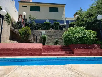 a swimming pool with a fountain in front of a house at Casa La Moradita in Villa Parque Siquiman