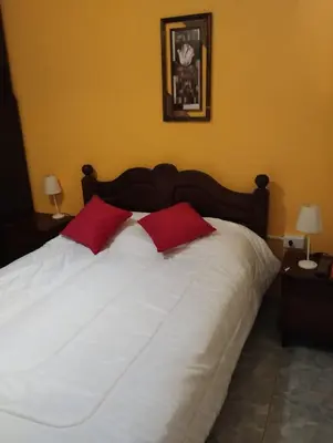 a large white bed with two red pillows on it at Casa La Moradita in Villa Parque Siquiman