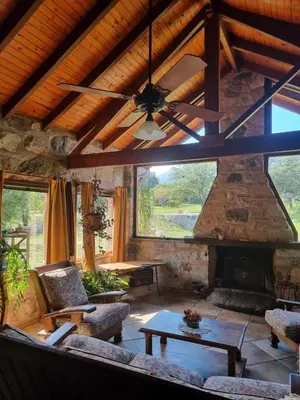 a living room with a stone fireplace and a ceiling at Las Veronas in Villa de Las Rosas