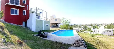 a house with a swimming pool next to a building at Casa de vacaciones in Villa Carlos Paz