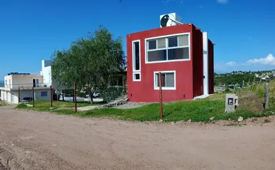 a red house on the side of a dirt road at Casa de vacaciones in Villa Carlos Paz