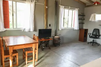 a room with a table and a desk with a television at El Ashva casa de campo y santuario de caballos in Las Calles