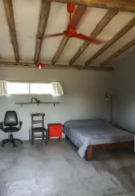 a bedroom with a bed and a chair and a window at El Ashva casa de campo y santuario de caballos in Las Calles