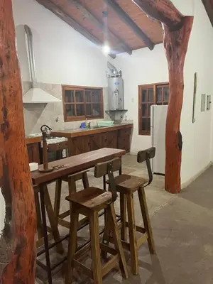 a kitchen with a wooden table and stools at Casona Las Calles in Las Rabonas