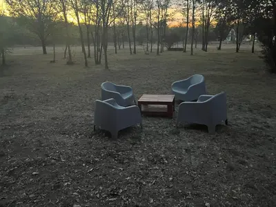 three chairs and a wooden table in a field at Casona Las Calles in Las Rabonas
