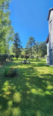 a grass yard with a building and trees in the background at Alojamiento en las sierras 2 dormitorios in Villa General Belgrano
