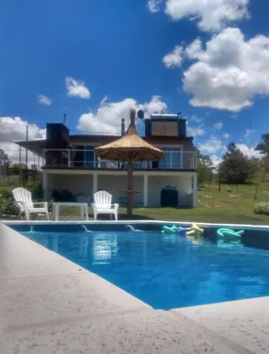 a house with a swimming pool and an umbrella at Alta vista casa de campo Tanti in Tanti